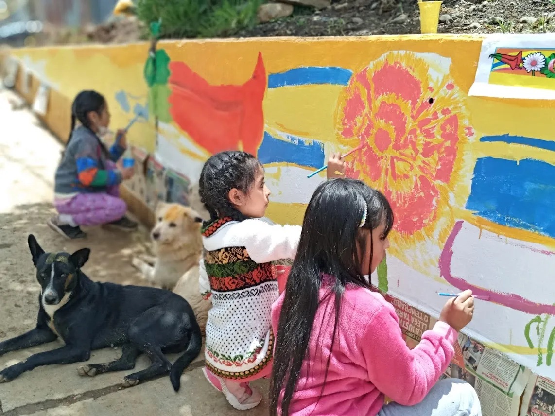 Niñas pintando un mural comunitario en Shancayán